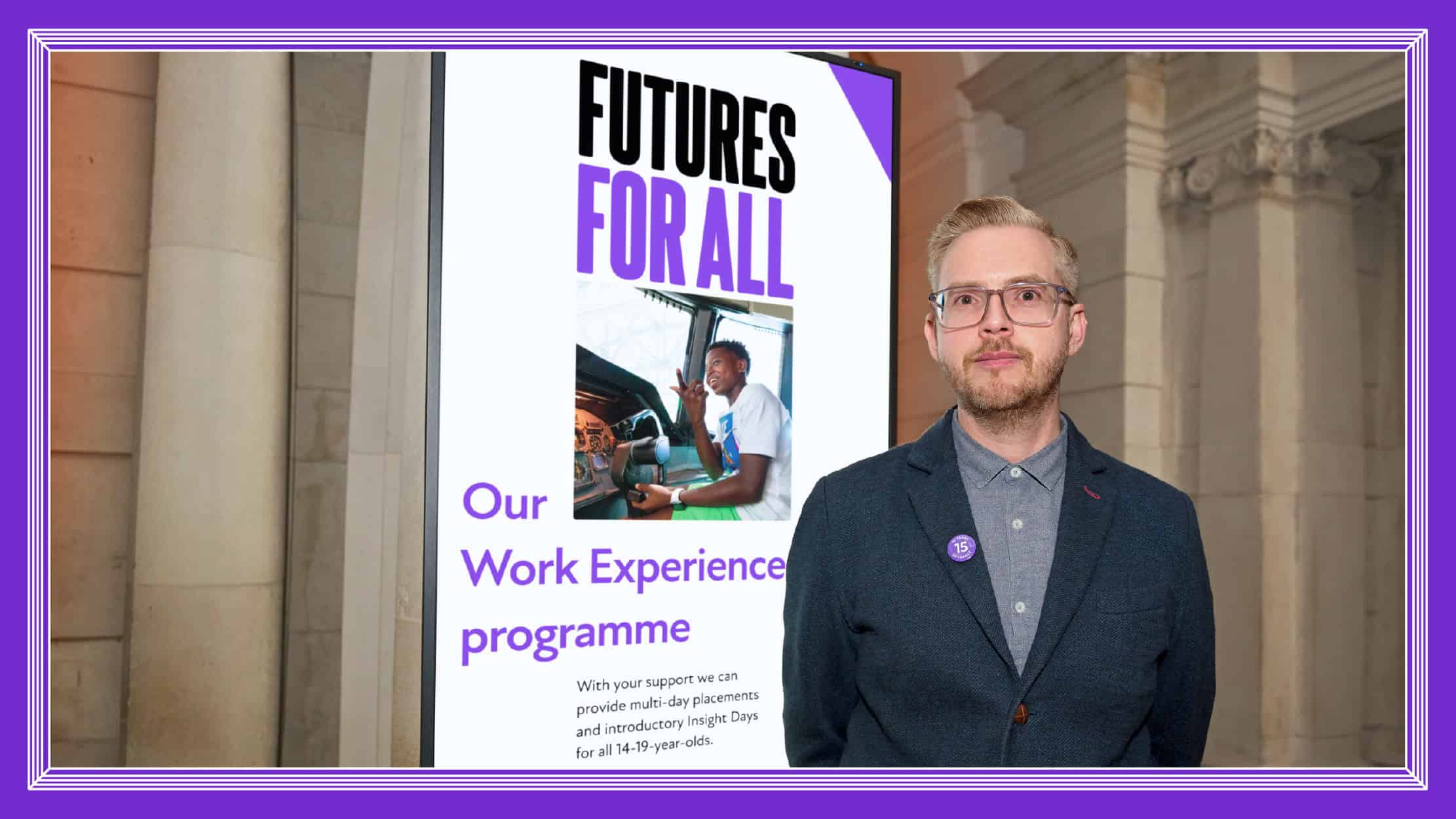 Neil Watts, Head of Brand standing in front of board with Futures For All branding.